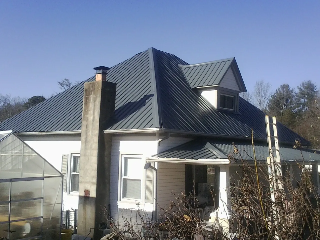 Dark blue standing seam metal roof on a white farmhouse with dormer — Slate & Tile Roof Repair by Roofing Brothers in Culver City