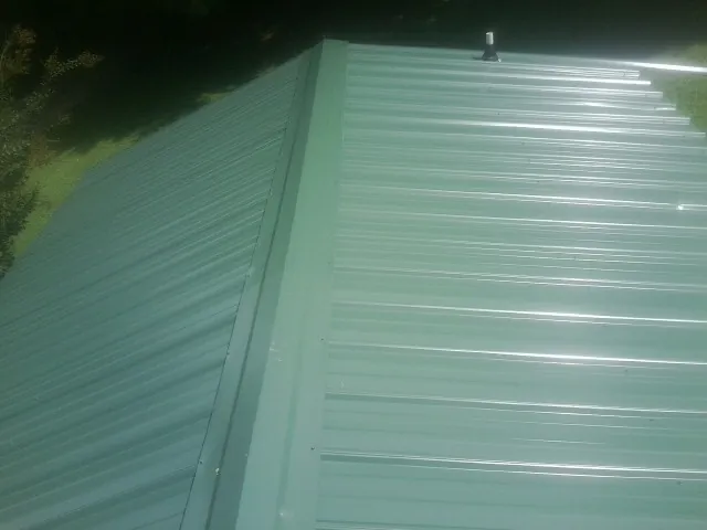 New green metal panels meeting at the ridge of a roof — Flat Roof Repair work by our crew in Culver City