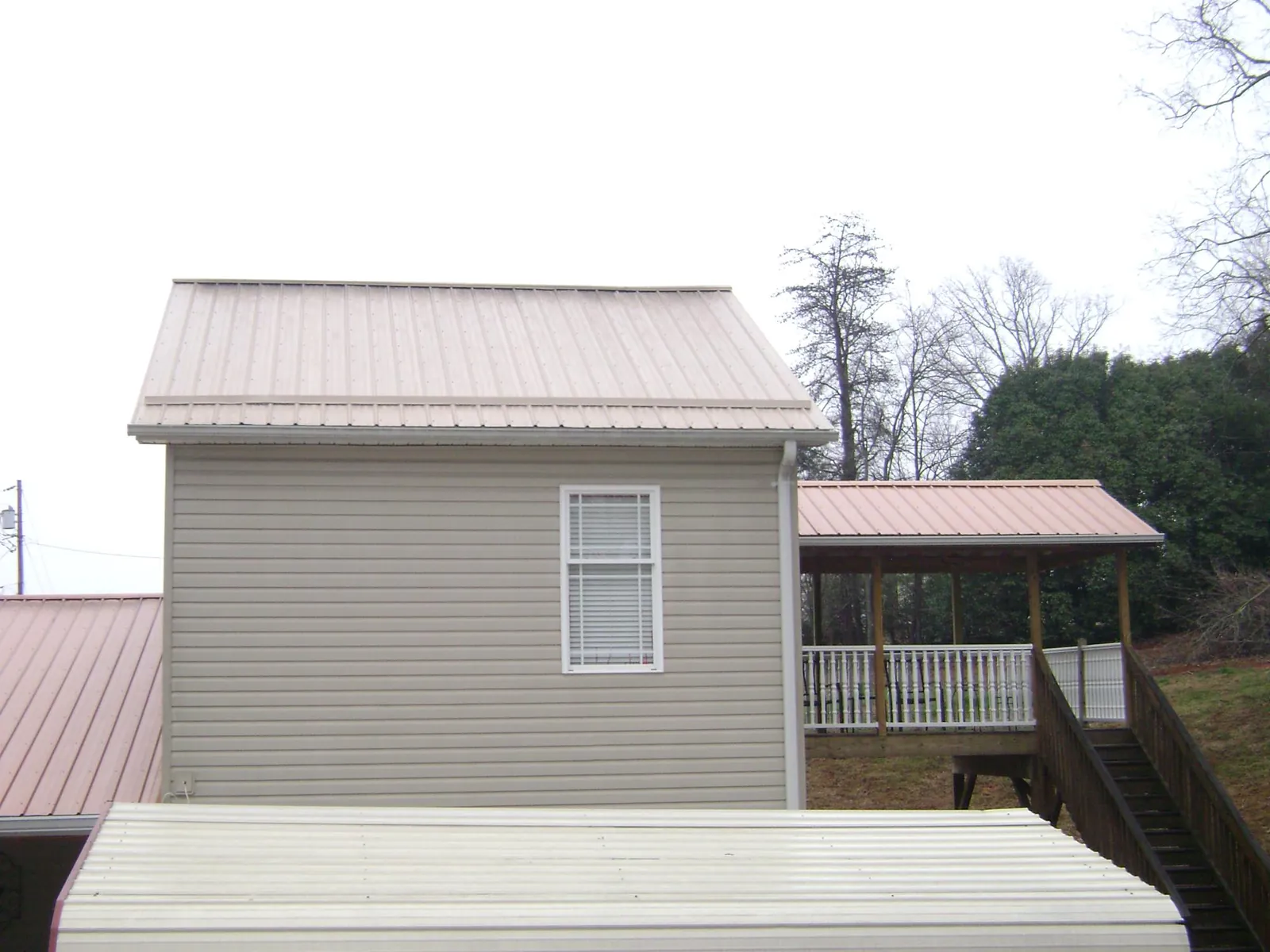 Tan metal roofs on a two story addition and attached porch, from a Roof Replacement job in Culver City