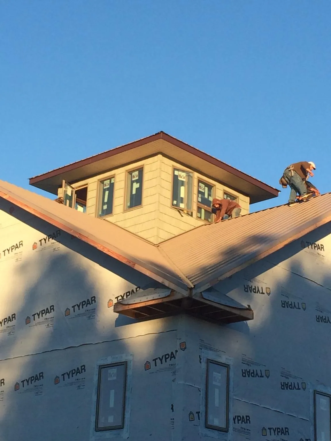 Roofers working around a rooftop cupola on a new metal roof at sunset — Roof Waterproofing in Culver City by Roofing Brothers